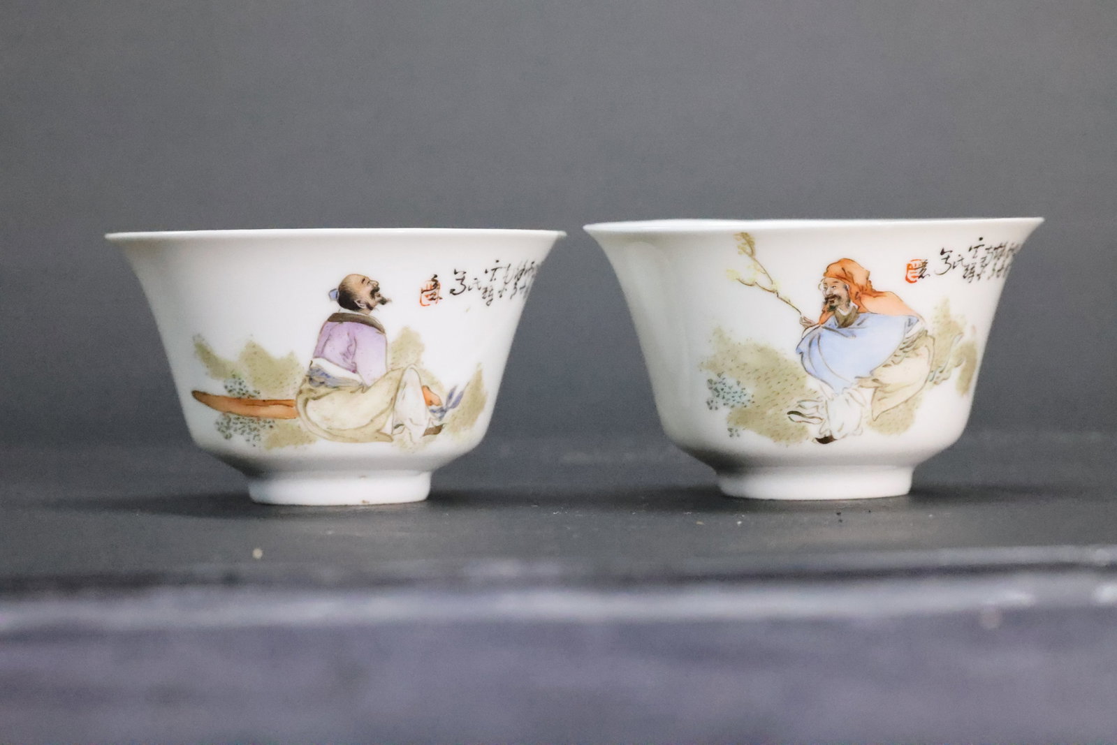 A Pair of Famille Rose 'Scholars and Calligraphy' Flaring Teacups, Republic Period: Estimated Date: Republican period (1912–1949). A pair of New Famille Rose (Xin Fencai) literary porcelain cups.Attribution: This matching pair of thinly potted porcelain cups was produced during the