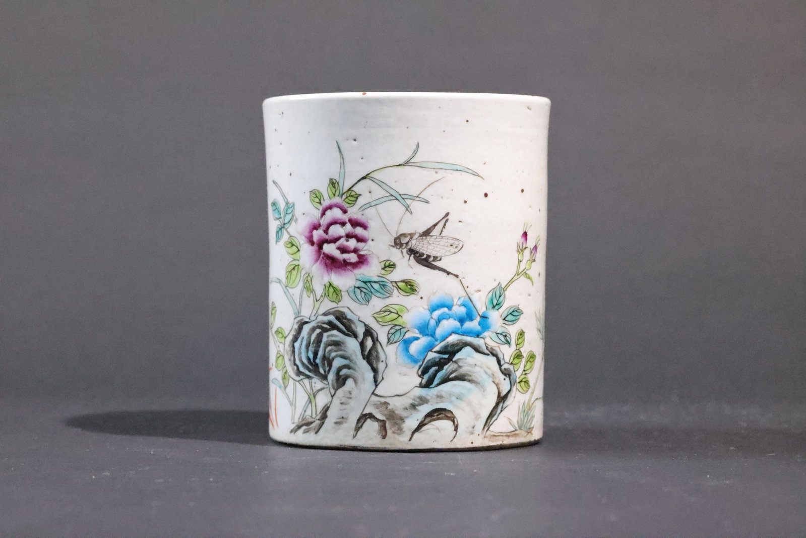 A Qianjiang-Enamel 'Insects, Rocks and Flowers' Brush Pot, Late Qing Dynasty: Estimated Date: Tongzhi to Guangxu period, Late Qing Dynasty (1862–1908). A shallow-enameled (Qianjiang Cai) porcelain brush pot for the scholar's studio.Attribution: This cylindrical white porcelai