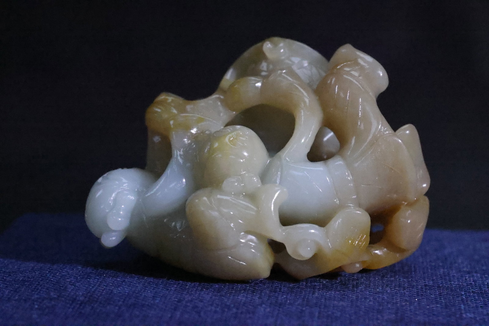 A White and Russet Jade 'Boy and Gourd' Carving: Estimated Date: Late Qing Dynasty. A Hetian celadon-white jade carved handpiece.Attribution: This folk-art jade handpiece is attributable to the late Qing Dynasty. Carved from Hetian celadon-white jad