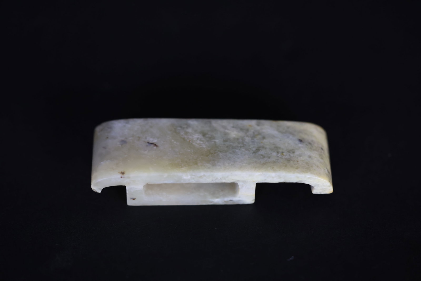 Carved White Jade Sword?Form Belt Ornament: Naturally aged patina with significant calcification, some areas of dark staining, stone veins present, minor wear to two tips, otherwise in excellent condition. H 1.4cm W 6.6cm
