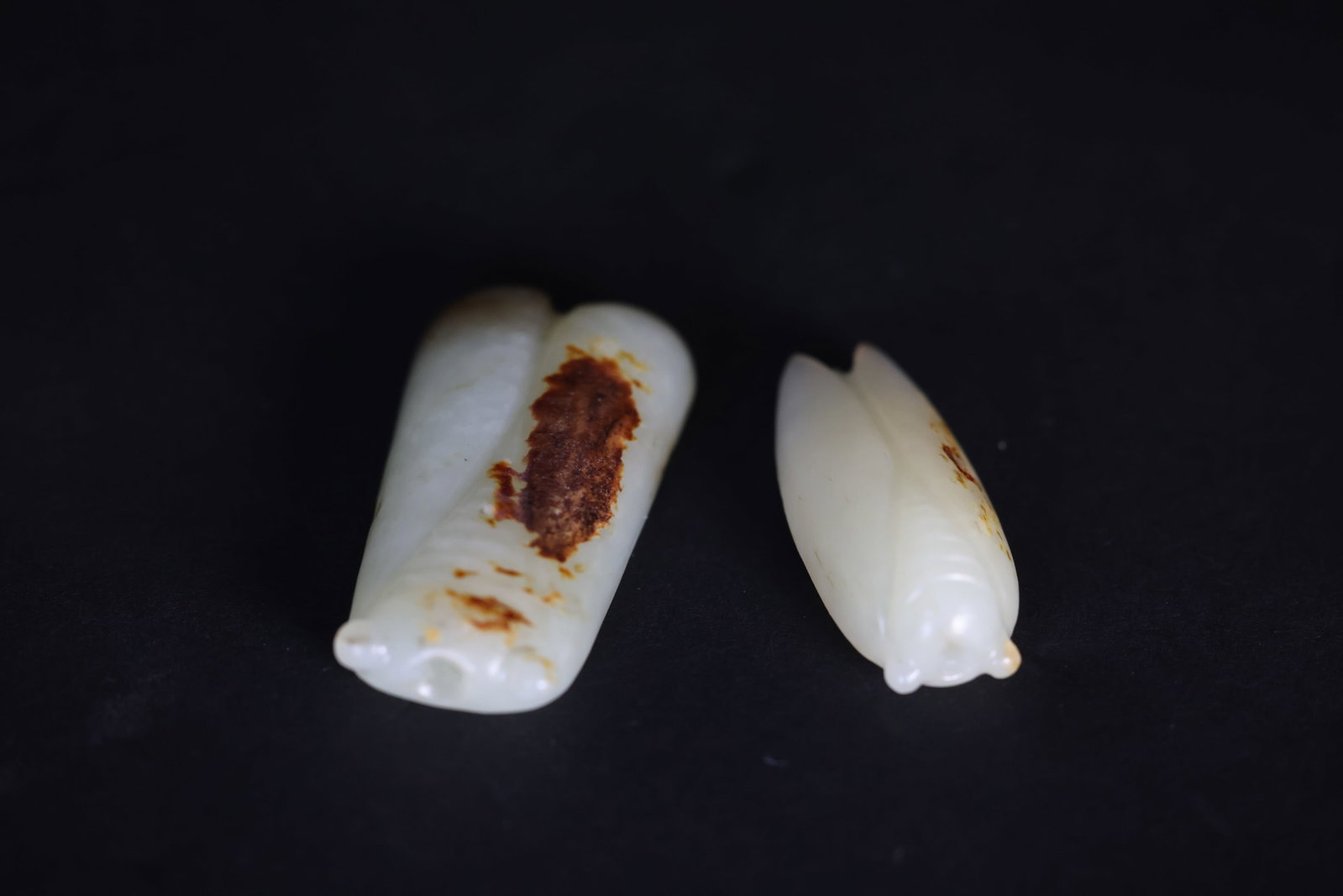 Pair of Small Jade Cicada Hand-Carvings Retaining Natural Skin: Naturally aged with patina and original skin coloration. 1. H 1.2cm W 5.6cm 2. H 1.3cm W 4.7cm