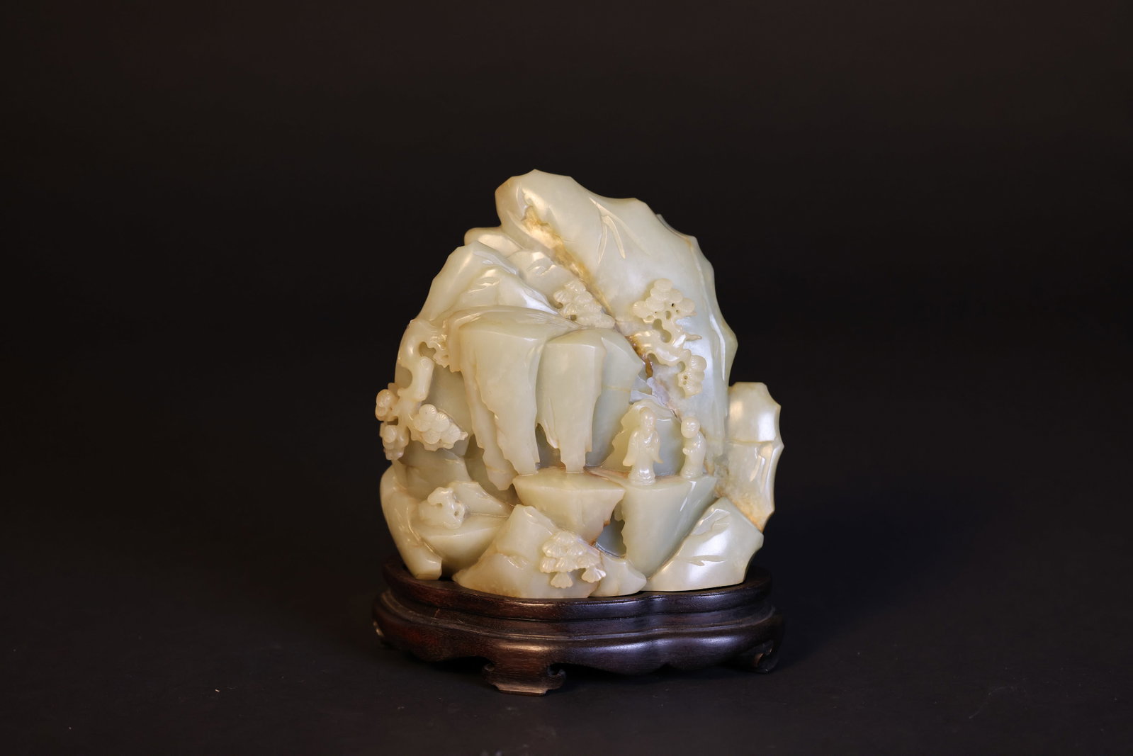 Qing Dynasty Hetian Pale Celadon-White Jade Immortal on Mountain Scholar's Rock with Pinewood Base: Naturally aged, patinated, with natural stone veining, otherwise in excellent overall condition. H 19.5cm. W 16cm