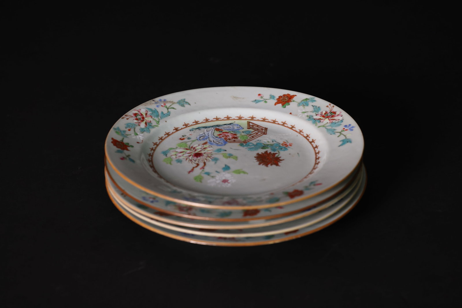 Mid-Qing Famille Rose Gilt-Decorated Floral and Rockwork Porcelain Dishes, Set of Five: Naturally aged with some color fading; one dish has several tiny nicks to the rim, smaller than a sesame seed. Otherwise, overall excellent condition. H 2.5cm. W 23.4cm