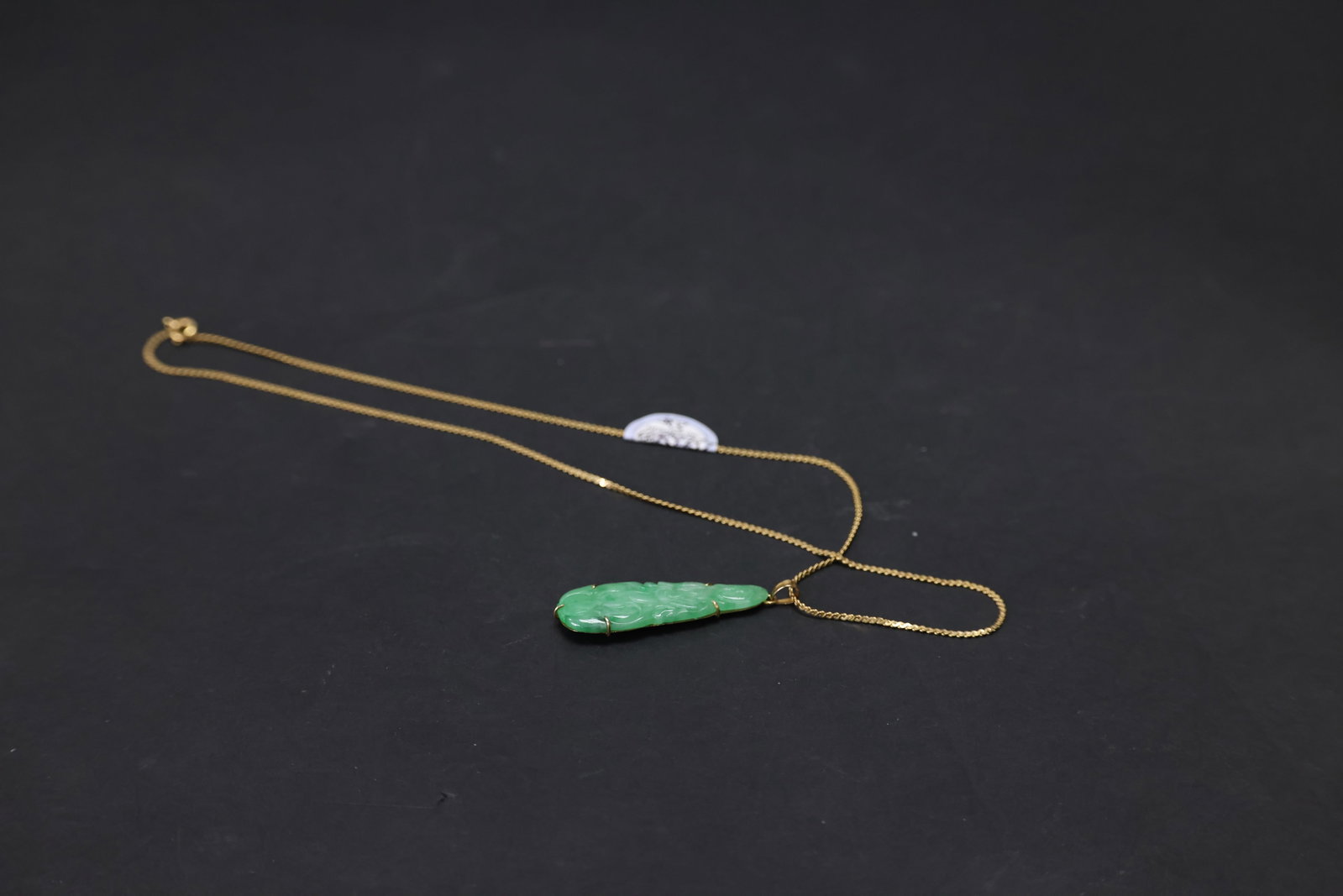 Qing Dynasty Jadeite Guanyin Pendant with 14K Gold Backing and 12K Gold Chain: Natural age-related wear, otherwise in excellent overall condition. H 4.2cm W 1cm