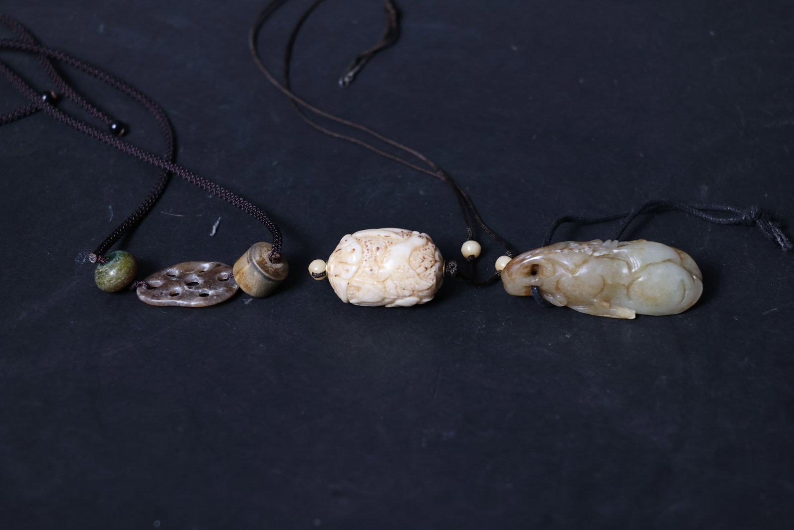 Group of Antique Pendants: Overall in well-preserved condition. The jade lotus slice shows natural patina and age-related veining. The bone ornament displays fine age lines without any chips or losses. The mythical beast