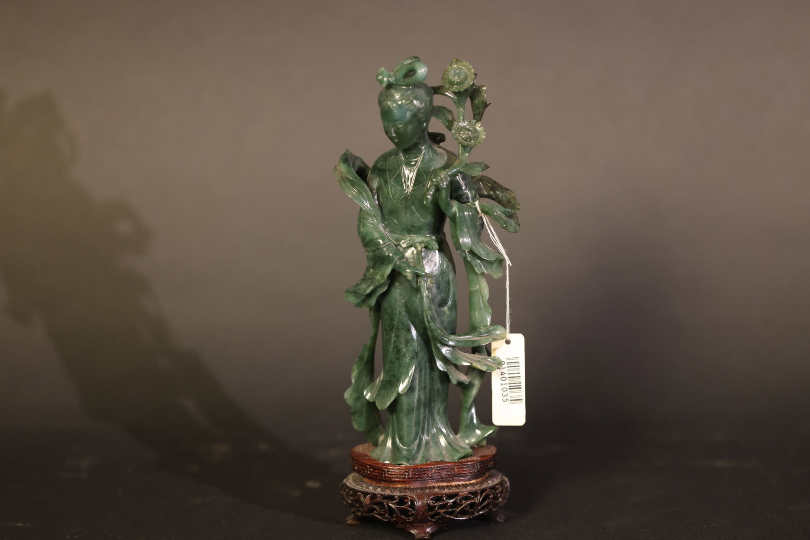 Carved Hetian Green Jade Figure of a Standing Court Lady Holding a Flower: Overall structure intact; minor old nicks to the slender petal ribbons, with no breaks or repairs; base complete with expected wear consistent with age. H 16cm W 6cm