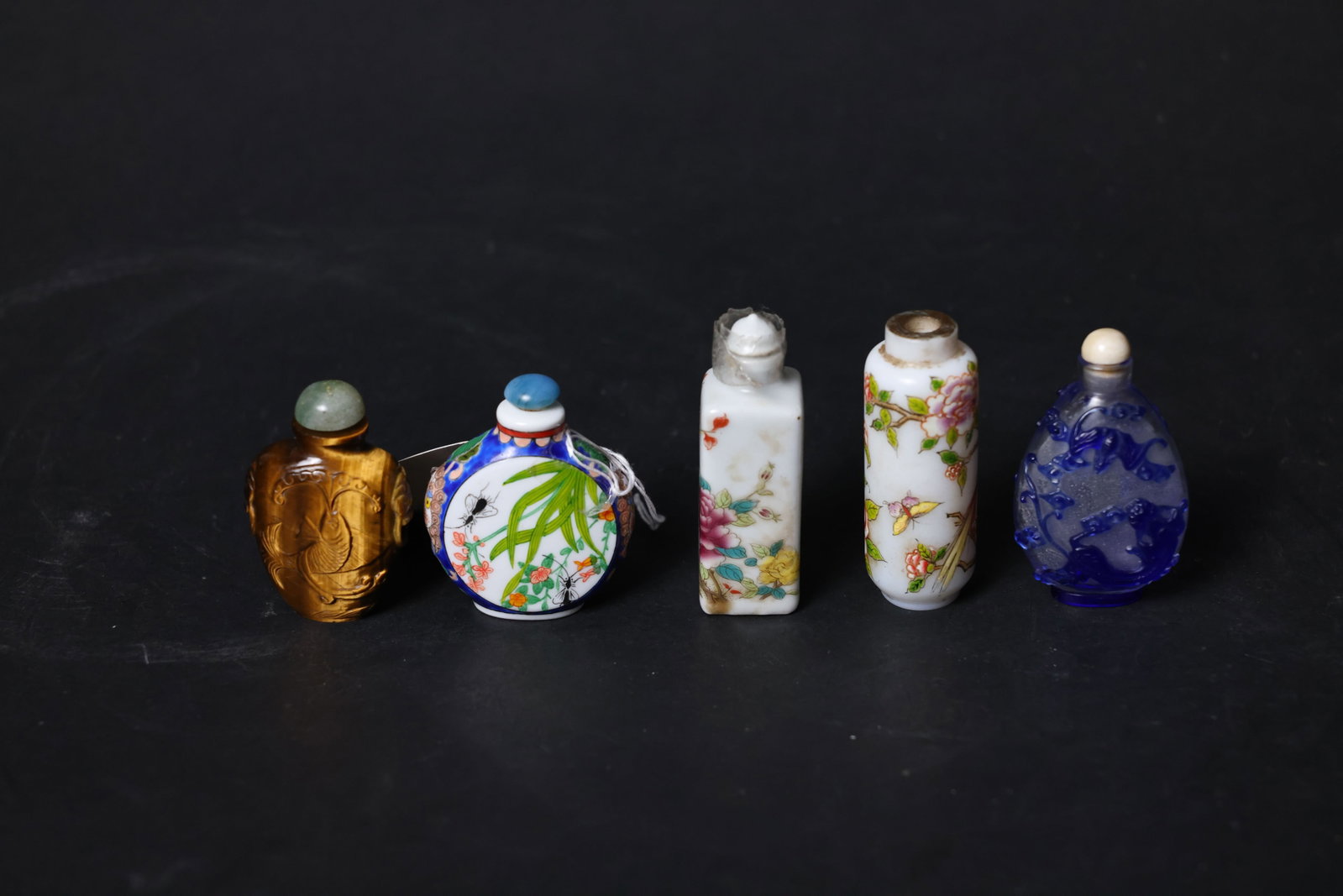 A Group of Chinese Snuff Bottles: Overall structurally sound with no cracks or chips; the fourth piece is missing its lid; the third piece’s lid shows signs of aging and adhesive residue; minor enamel wear to the decoration; rim