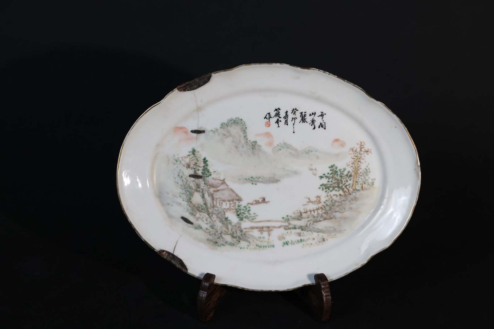 Late Qing large pale overglaze-enamel landscape lobed?rim oval platter: The body features several old copper staples for reinforcement along areas of previous damage. There are repairs to the rim, and the painted decoration remains in generally good condition. The base