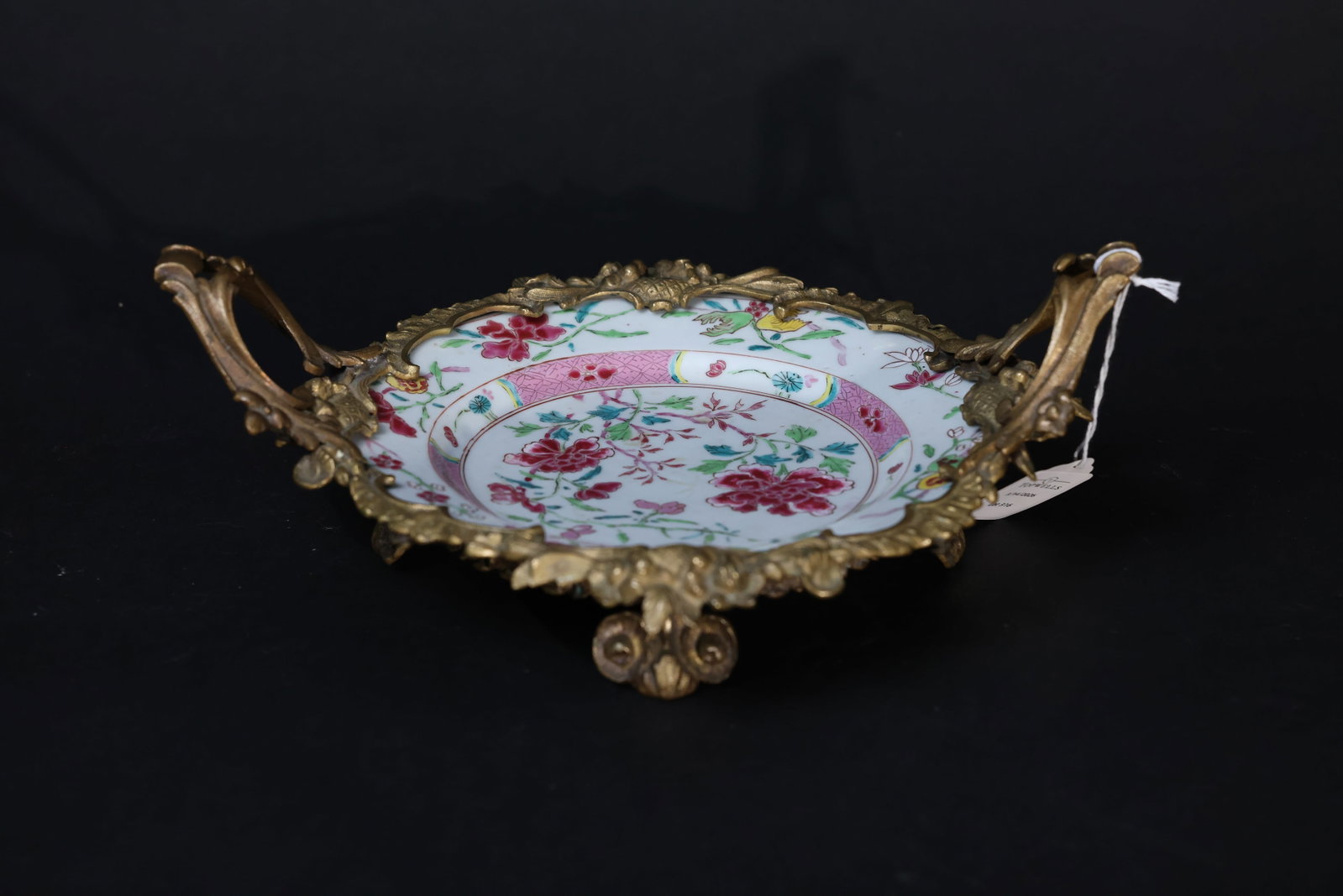 Qing Dynasty, Yongzheng Period Famille Rose Peony and Floral Dish: The porcelain dish is well preserved, with only minor surface wear consistent with age and use; no significant cracks or major chips observed. The gilt bronze shows some localized wear to the gilding,