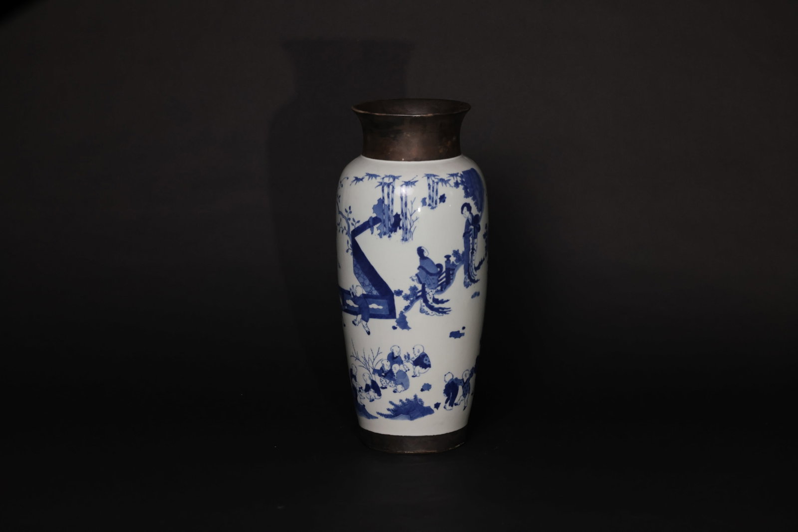 Blue and White Cylindrical Vase Depicting Court Ladies and Children at Play: Mouth and base have later-added copper mounts; copper sheathing is a later addition. The main porcelain body and glaze are intact, with no visible cracks or major chips. The foot rim shows typical old