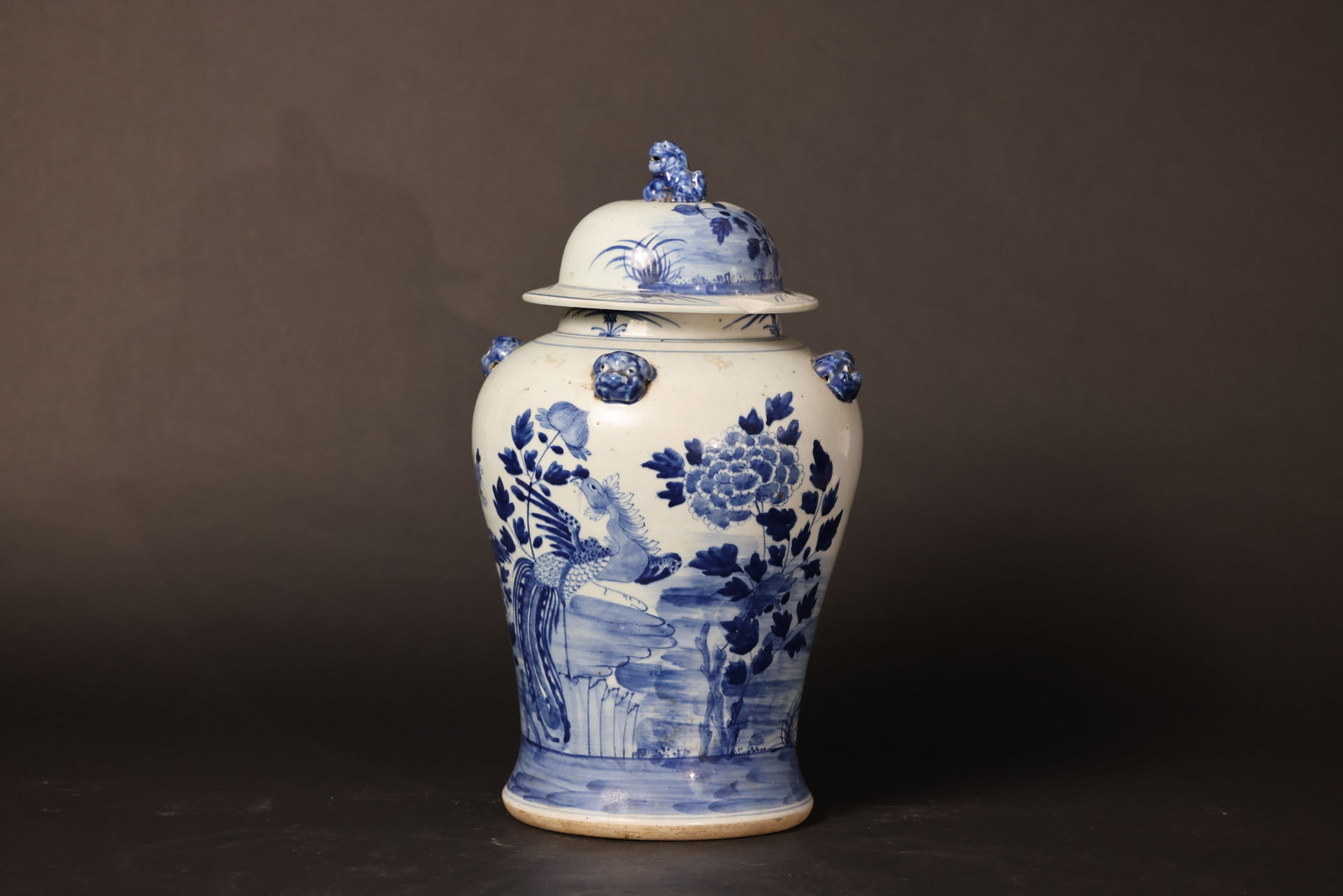 Blue-and-White Phoenix and Peony General's Jar with Four Beast-Head Handles and Lion Finial: The rim of the lid has chips; the beast-form handles show areas of glaze loss and wear; the body has age-related stains; no major cracks to the main vessel; the lion finial is intact. H 42cm W 21cm