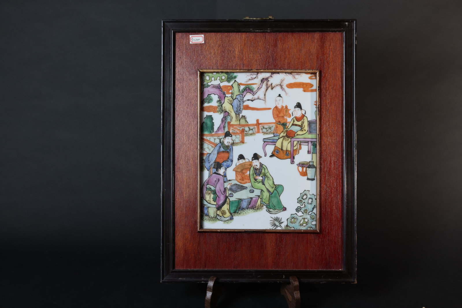 Republican Period Famille Rose Porcelain Plaque: Scholars Playing a Board Game in a Courtyard: Porcelain plaque is intact with no cracks or chips; enamels show natural age-related wear. Wooden frame has areas of paint loss and surface wear, but no breaks. H 49cm W 37cm
