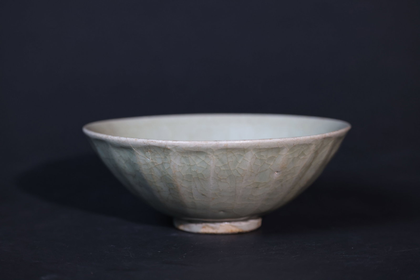 Yuan–Early Ming Longquan Kiln Carved Lotus-Petal Celadon Bowl: The vessel is of complete form, with a long firing line along the body, minor fritting to the rim, an old crackle to the glaze, and traces of burial encrustation. H 6.5cm W 16.5cm