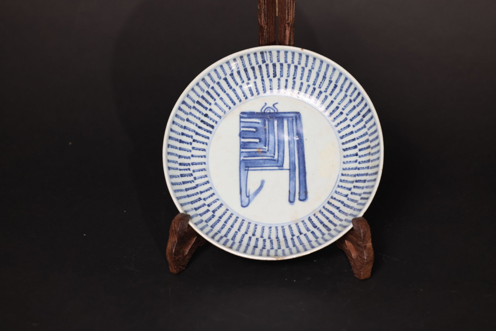 Mid-Qing blue-and-white porcelain dish with Sanskrit "Shou" (longevity) character: Rim with firing lines and minor chips; obvious signs of use. Glaze with black spots and earth encrustation. In worn antique condition. H 4cm W 20cm