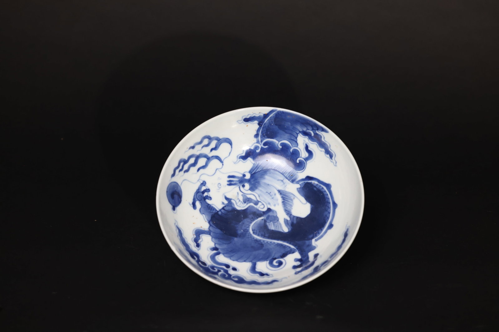 Mid-Qing Underglaze-Blue "Dragon Crossing the Wall" Shallow Bowl: There is a small chip to the rim, with some wear marks inside the bowl from use. No hairlines detected. The foot shows obvious signs of age and use. H 7.5cm W 21.5cm
