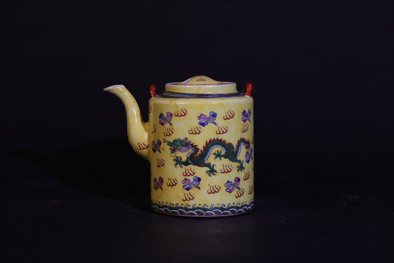 Jingdezhen Yellow-Ground Famille Rose Dragon Bail-Handled Teapot: The body is intact; the lid has a visible firing line crack. Minor enamel wear in some areas. The foot shows age-related patina from use. No significant chips or losses. H 16.5cm W 18cm