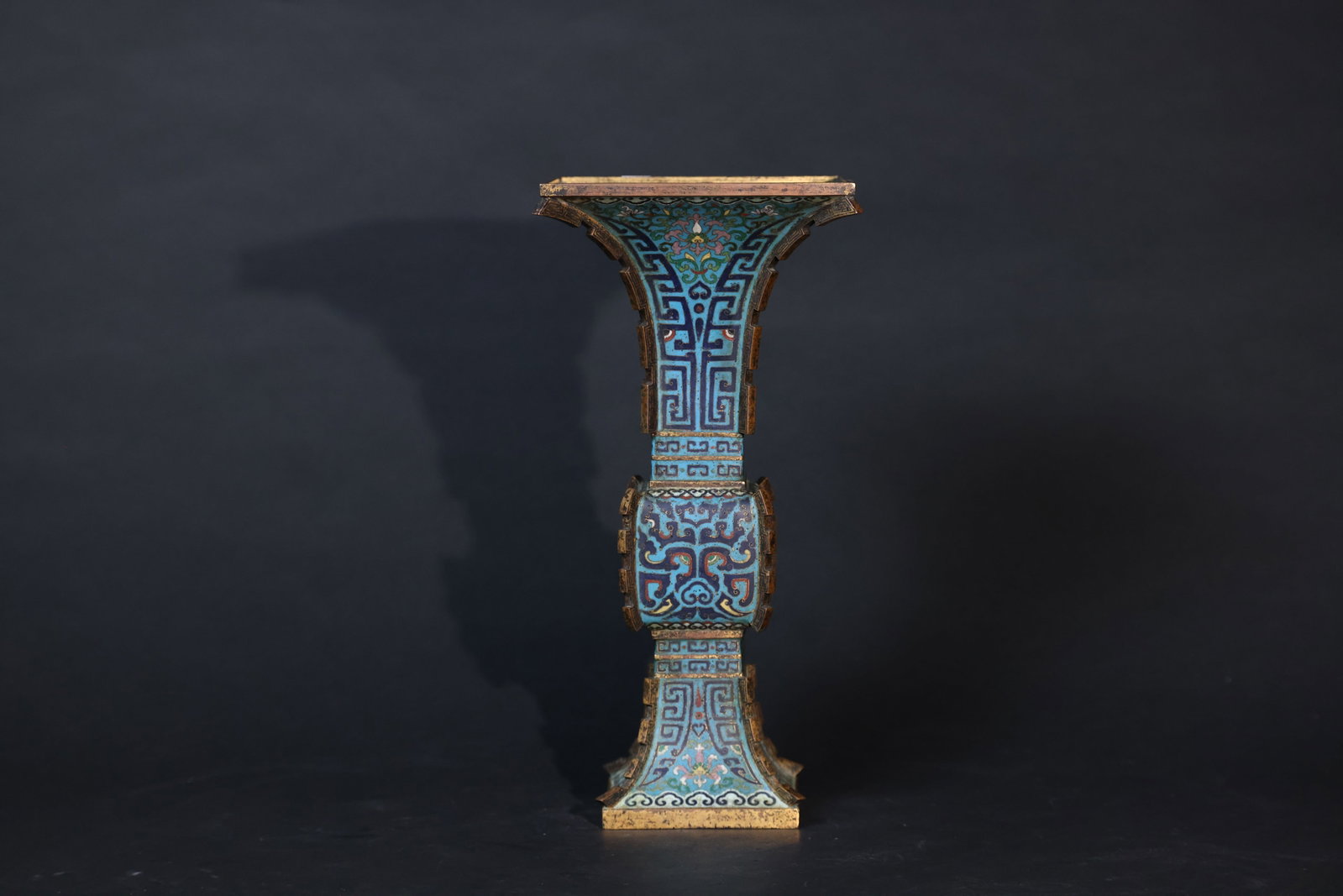 Qing dynasty cloisonne over copper square gu with taotie masks and projecting blade terminals: Overall intact with partial gilt wear, minor enamel losses, some age-related breaks to the cloisonné wires, no significant cracks or repairs, and a rich patina. H 34cm W 16cm