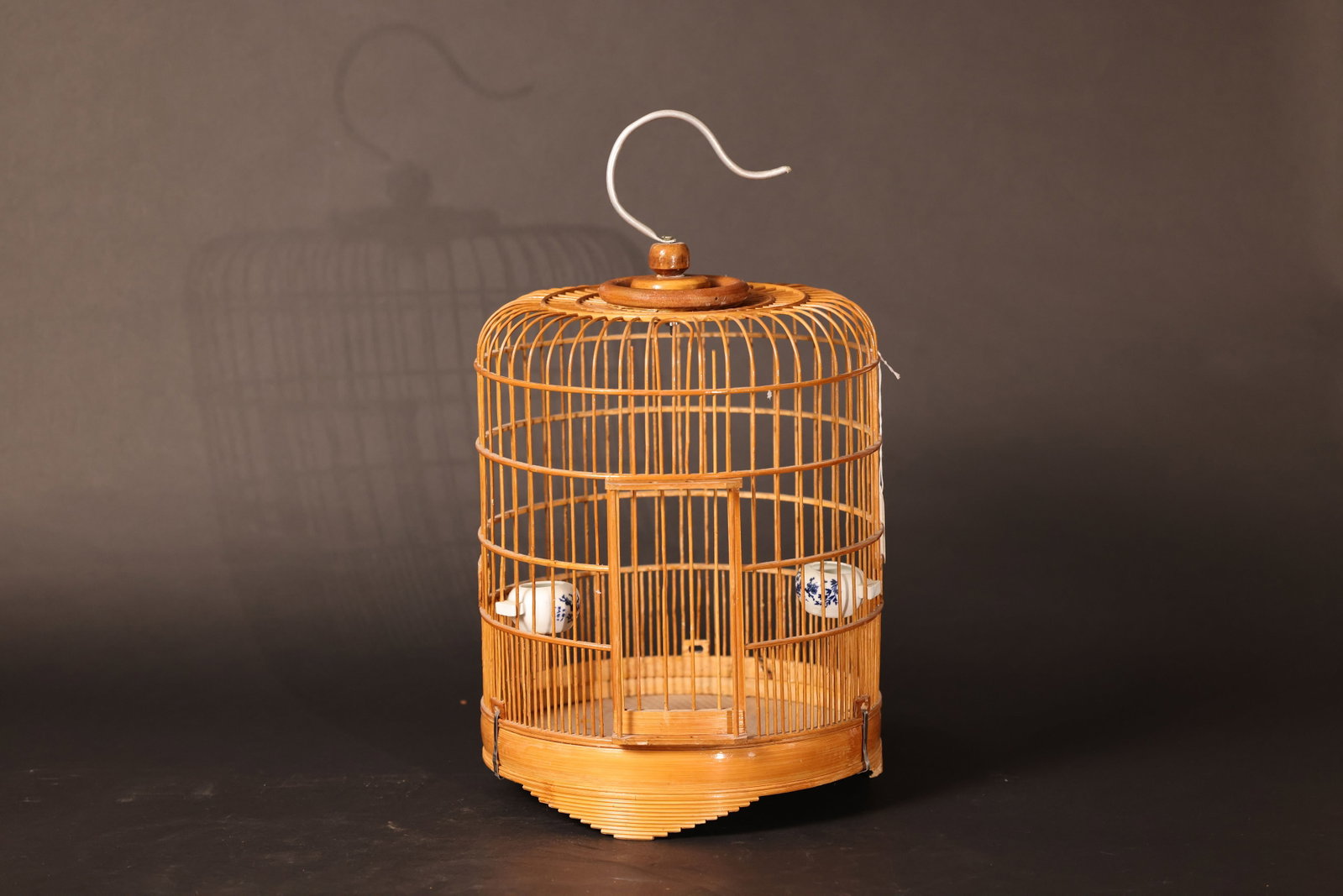 Unadorned Bamboo Birdcage: Overall structure is intact, with a warm, natural bamboo tone. Minor signs of normal use. Bamboo strips are undamaged with no breaks or losses. The food container is complete with no restoration. H