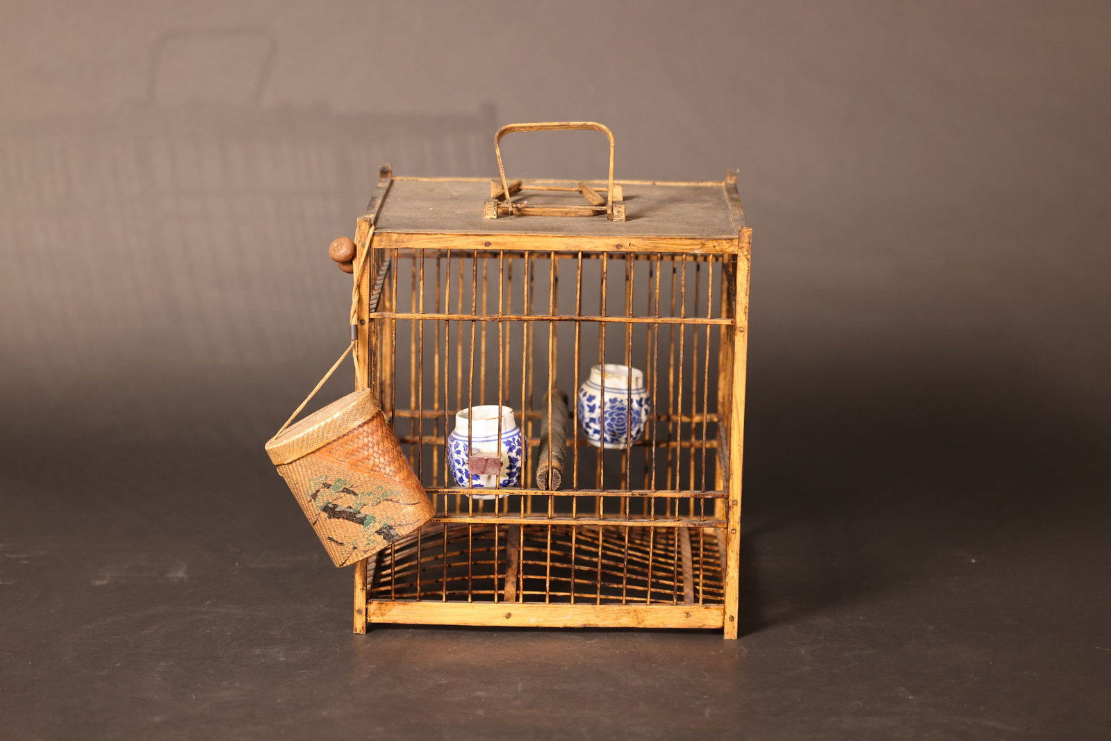 Antique Square Bamboo Birdcage (Old Bamboo): With original patina from age and use; some old marks on the bamboo strips, but no major breaks. The food container is intact. The small painted bamboo basket shows some wear to the decoration, but