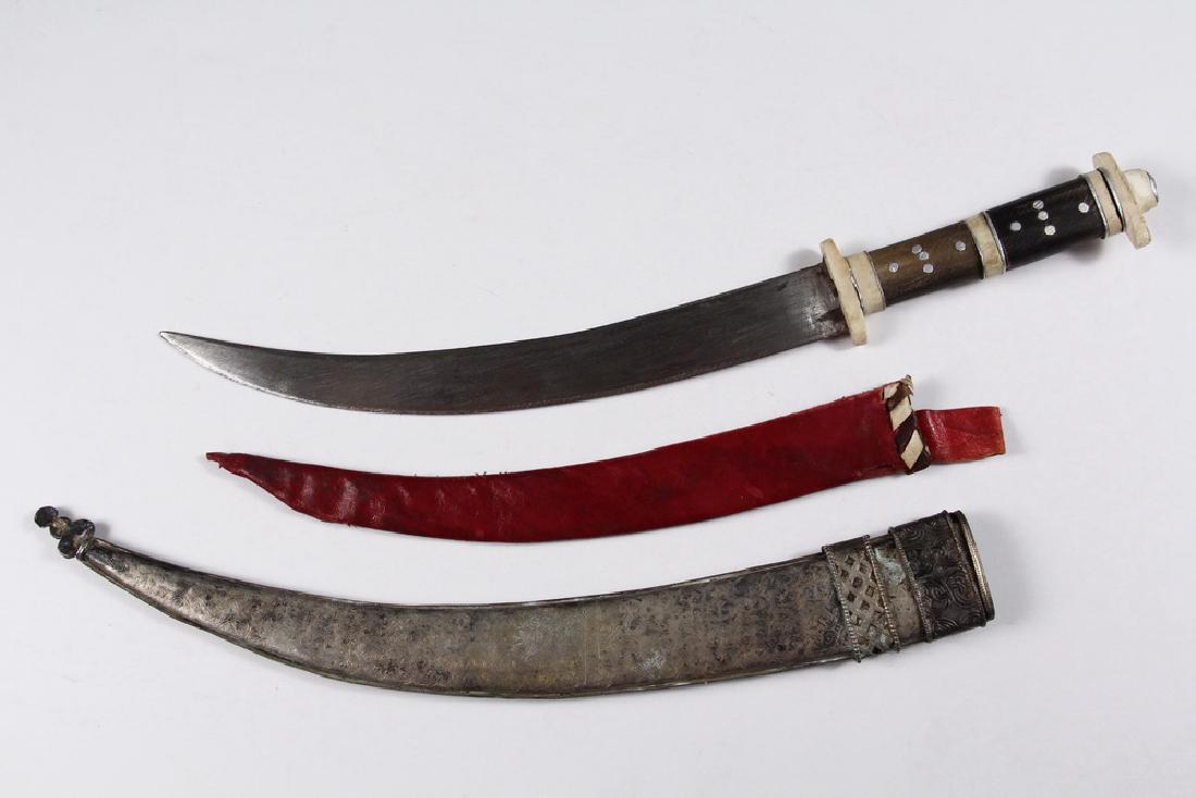 ARABIAN KNIFE: Balkan / Turkish Jambiya - Yatagan Knife, tourist grade, with ground steel blade, sharp on both edges, wood and bone handle, crimson leather sheath inside an engraved and cast silver scabbard, early 2