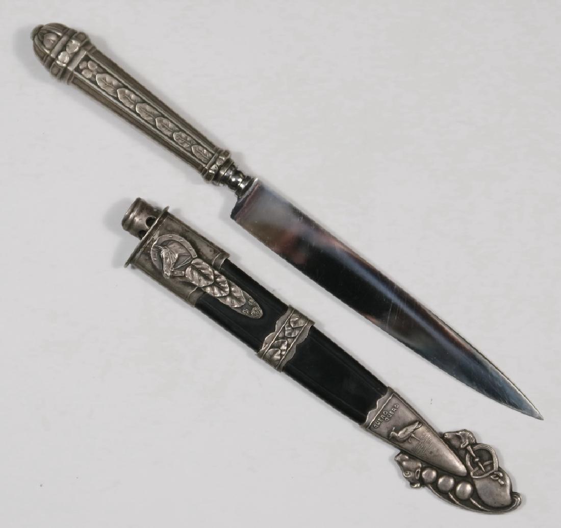DAGGER: Silver Mounted Argentinian Gaucho Dagger by Quero-Quero with Inox Blade, sheath is decorated with horse head, bird and cow head motifs, marked 'Quero Quero' on blade and sheath, 11 1/2" long inside sh