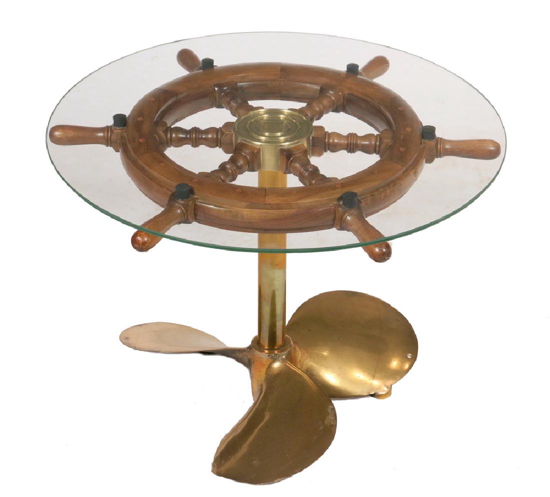 SHIP'S WHEEL COFFEE TABLE: Low Round Table made up from a mahogany ship's helm with brass hub, on a solid bronze propellor and shaft, with 1/4" plate glass top, 18 1/2" tall, 24" diam. Very good condition.
