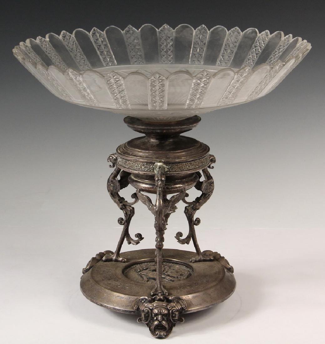 SILVER PLATE & GLASS COMPOTE: Ornate Victorian Compote with Silver Plate Base having three Gryphon form legs, on platform vase with classical relief and three head form legs. The dish is cut glass with a scalloped edge. 12 1/2" x 