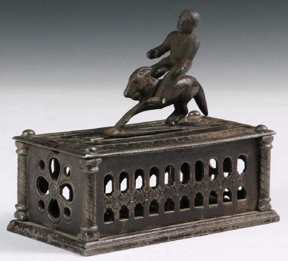 MECHANICAL BANK: "Bucking Mule" Cast Iron Mechanical Bank by The Judd Mfg. Co., New Britain, CT, original surface with traces of black paint, 4 1/4" high, 4 3/4" x 2 3/8". Repairs, replaced figure.