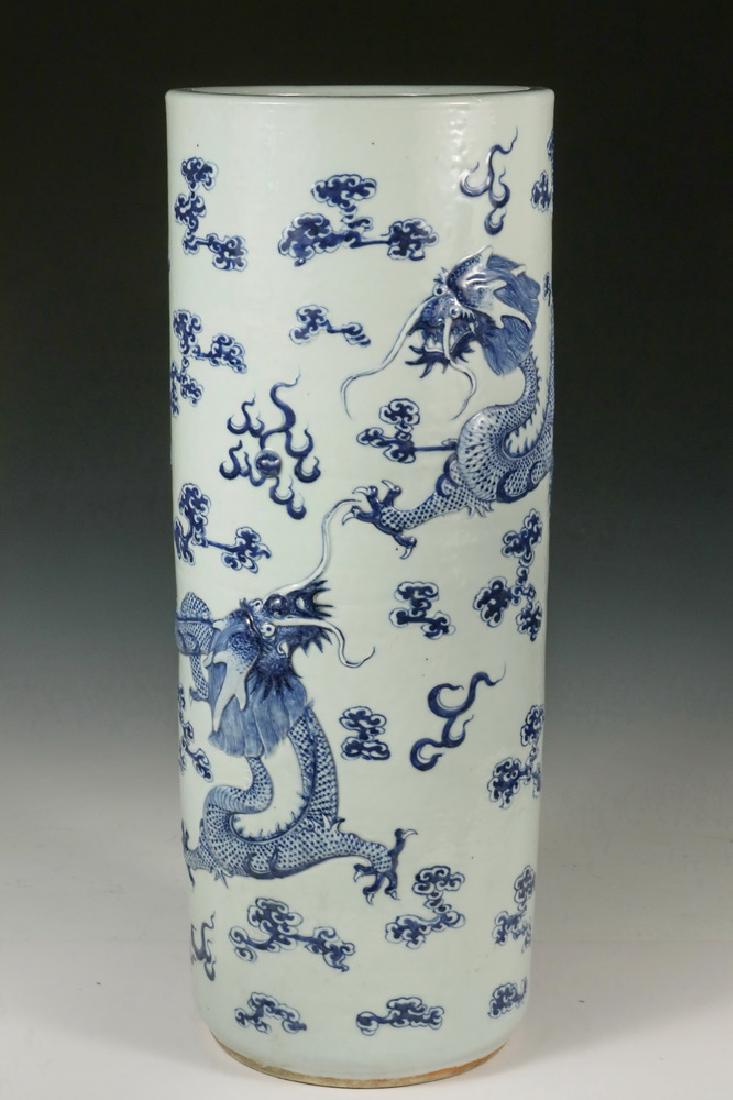CHINESE PORCELAIN UMBRELLA STAND: Early 19th c. Cylindrical Porcelain Jardiniere with raised blue and white decoration of two opposing dragons among a field of flaming pearls and clouds, 24 1/4" tall, 9 1/4" diam. Small hairline to ba