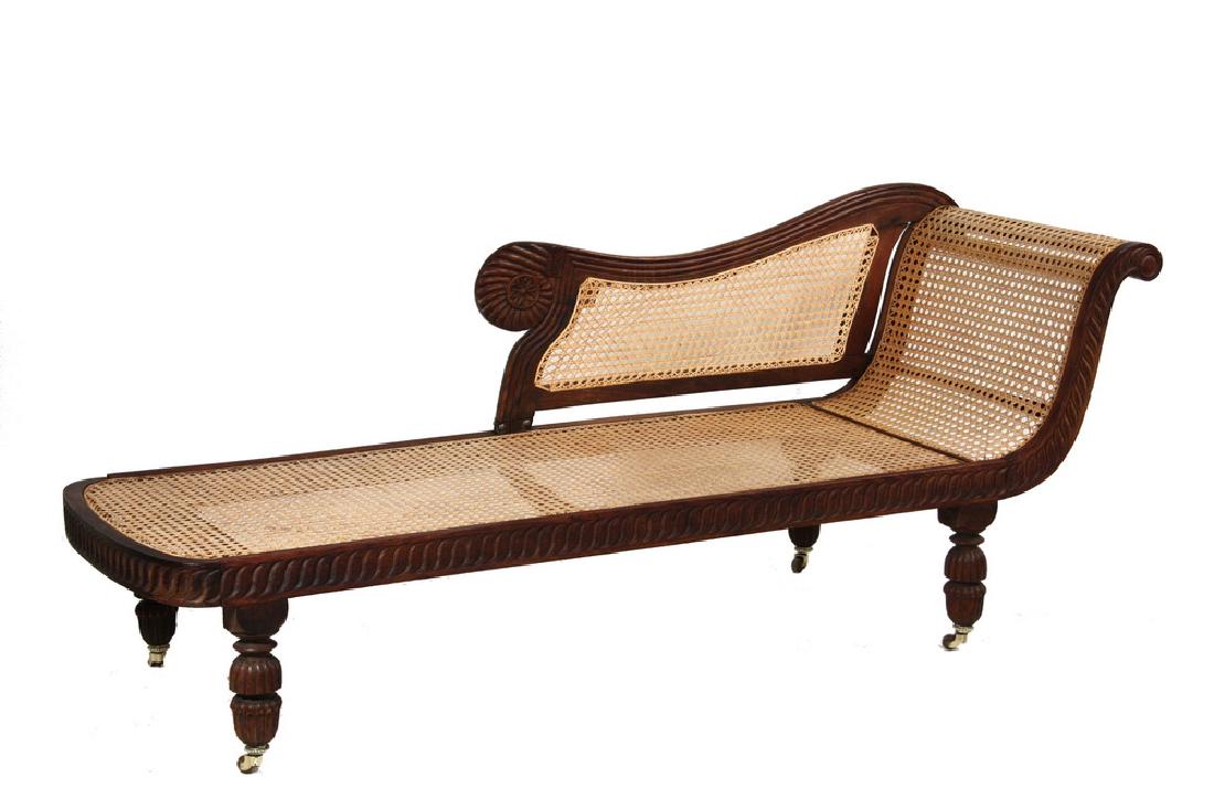 RECAMIER: Circa 1830 Chinese trade padouk wood elaborately carved and caned recamier retaining its original brass ferrules and castors. 30" (76.2 cm) high, 75" (190.5 cm) long. Several old repairs, recaned.