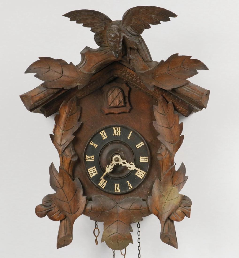 CUCKOO CLOCK: 19th c. German Black Forest Carved Wooden Cuckoo Clock, with spread wing bird cornice and leaf decoration, iron chains and pine cone form iron weights, leaf form pendulum, 16 1/2" high (without weight