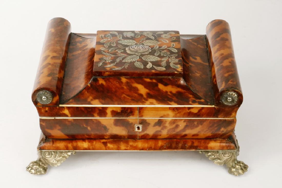 ENGLISH REGENCY TORTOISESHELL JEWELRY CASKET: Neoclassical Sarcophagus Form Box, with engraved floral abalone inlay on the flat center top, rolled ends with silver buttons, concave lid over convex sides resting on molded base with silver lion paw