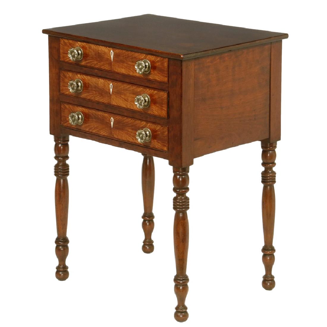 THREE-DRAWER SHERATON STAND: Early 19th c. New England Work Stand in walnut, with thin overhanging top, drawers faced with booked feather veneer, diamond inlaid escutcheons, pressed brass rosette pulls, ring and urn turned legs e
