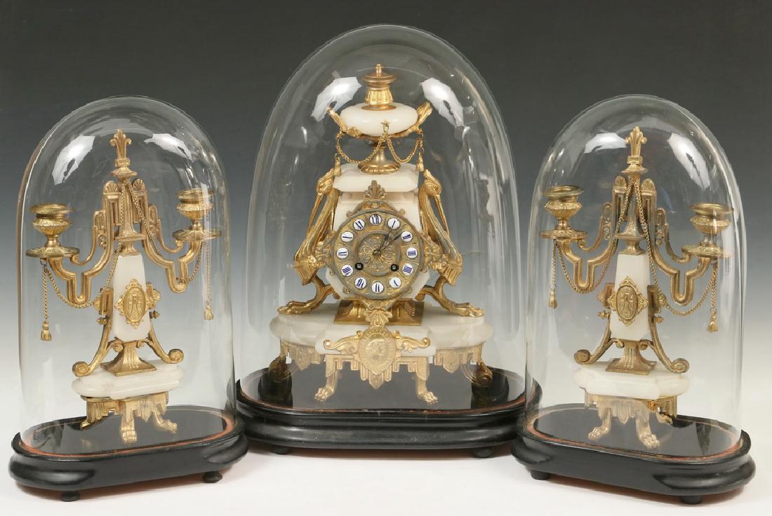 FRENCH CLOCK AND CANDELABRUM DOMED GARNITURE SET: Ornate Greek Revival Alabaster and Dore Mounted Clock and Matching Two-Stem Candelabrum, all on black platforms with glass domes. The clock works marked 'J. George, Horologie et Jouliere, Dunkerque, 8