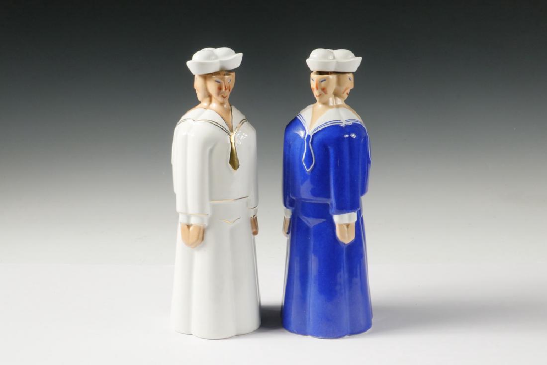 (2) ROBJ PORCELAIN SAILOR DECANTERS: A Pair of Sailor Form "Les Trois Matelots" Liquor Decanters by Robj of Paris, France, ca. 1930s, each having three sailors standing back to back, one in dress whites with gilding, the other in dress b
