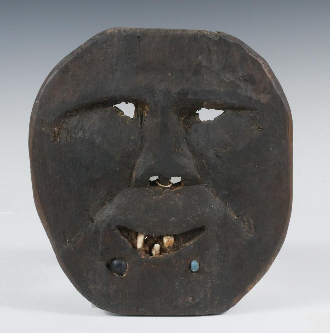 GREENLAND MASK: 19th c. Carved Wood Plank Mask with features defined in shallow relief, eye and nose openings, smiling mouth with inset teeth, two inset trade beads, 9 1/4" x 8", 3/8" thick. Nice age and use patina.
