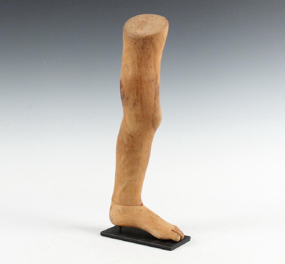 VINTAGE MEXICAN MILAGRO: Late 19th c. Votive of a Man's Left Leg, in unpainted carved wood, on a museum stand. This is an ex-voto offering created in the hope of healing the depicted imb. 16" tall. Good condition.