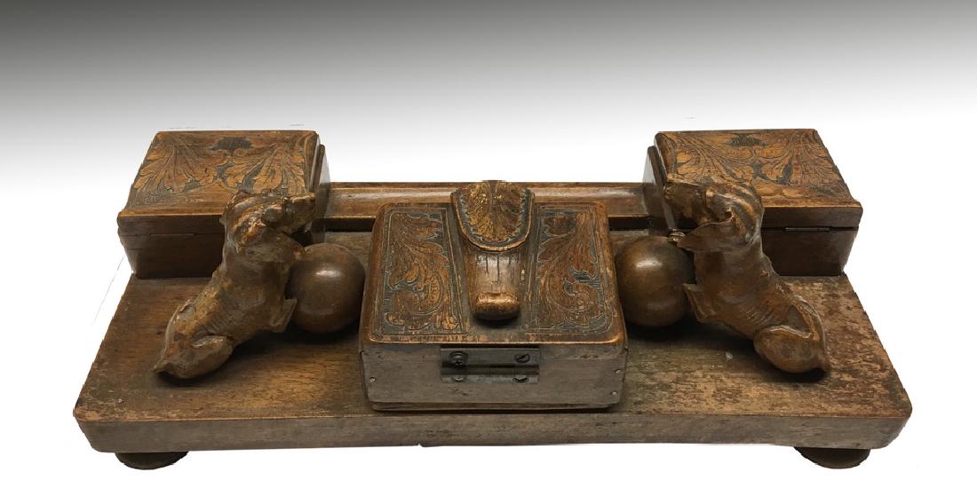 INKWELL: Ca. 1920s, Hand Carved Mahogany Double Inkwell featuring two dogs with front paws on balls, central stamp box on back, inkwells to sides at front. Low relief foliate carving to all lids, integral pen 
