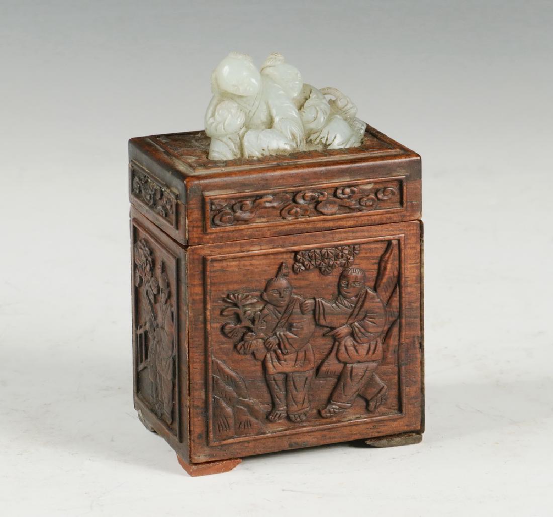 CHINESE WOOD AND JADE BOX: Rosewood Box with white Jade Finial of a Loving Couple, the box carved in relief with scenes of domestic bliss, 4 1/8" tall overall. Good condition.