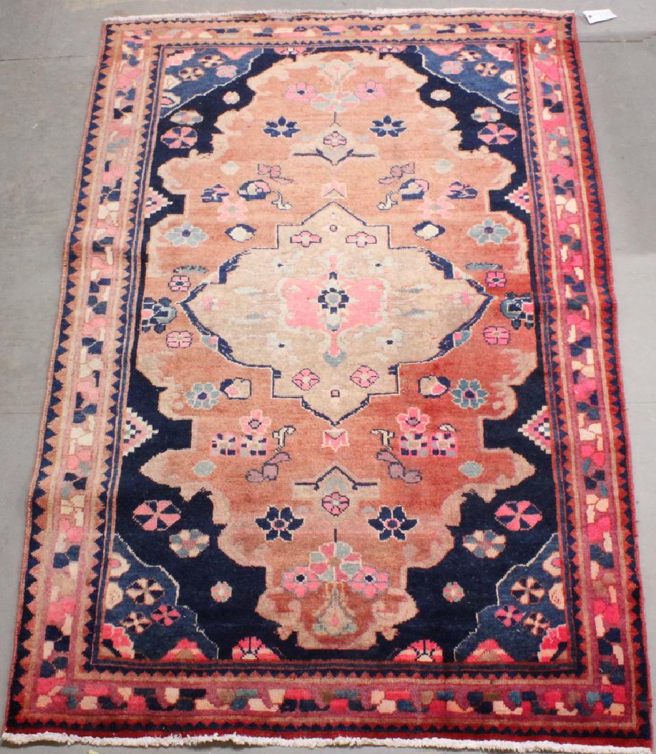 NORTHWEST PERSIAN RUG - 4'-8" x 7': Iran, 20th c., a lobed and gabled salmon floral medallion set on a faded red field, Persian blue spandrels, multicolor geometric border. Even wear, faded.