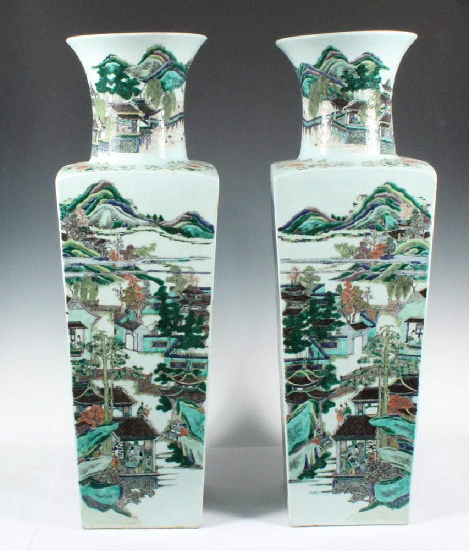MONUMENTAL PAIR CHINESE PORCELAIN FLOOR VASES: Pair of Chinese Famille Verte Porcelain Square Floor Vases with figural and landscape decoration depicting village scenes, on carved wooden stands, bases with unglazed foot with recessed glazed center