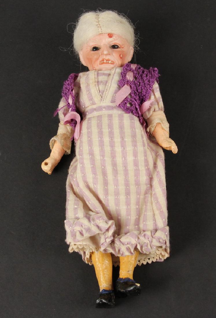 BISQUE HEAD 'HEXE' WITCH DOLL: Late 19th c. German Bisque Socket Head 'Hexe' Doll, clothing appears to be original, with glass eyes, red warts, hooked nose, and crooked teeth, grey mohair wig, composition body and painted shoes, ba