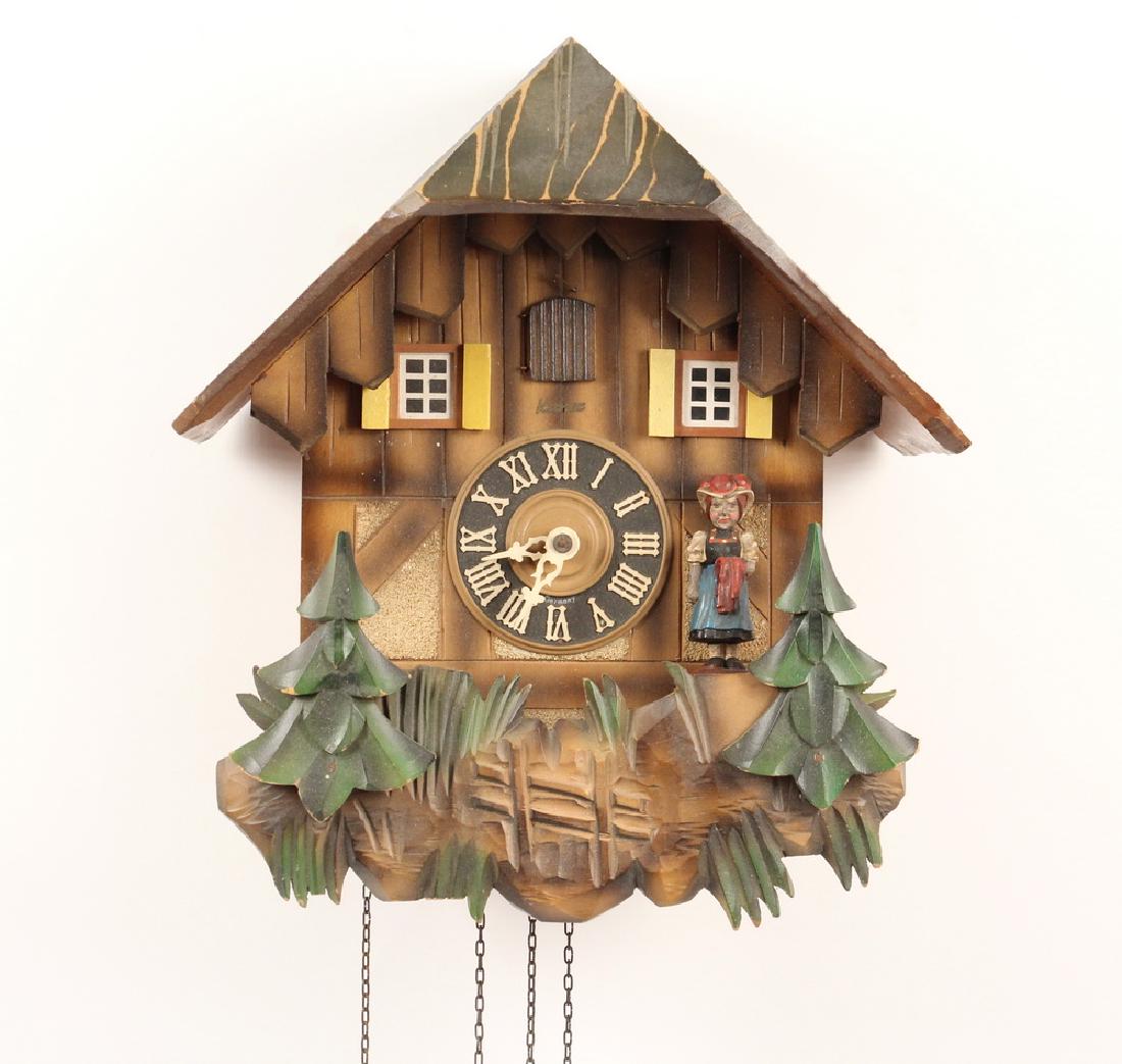 CUCKOO CLOCK: Wall mounted German cuckoo clock by Kuner, triple weight thirty hour movement with cuckoo and music box dancers, Swiss chateau style with applied carved trees, 12" high, 11" x 8". Missing male dancer.