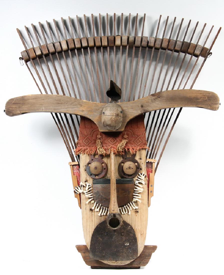 FOLK ART ASSEMBLAGE: 'Head Man', an assembled mask by Nancy McGuire of Damariscotta, Maine, made up from garden tools, kitchen implements and found objects, real tooth necklace, 36" tall. Two missing slats at top.