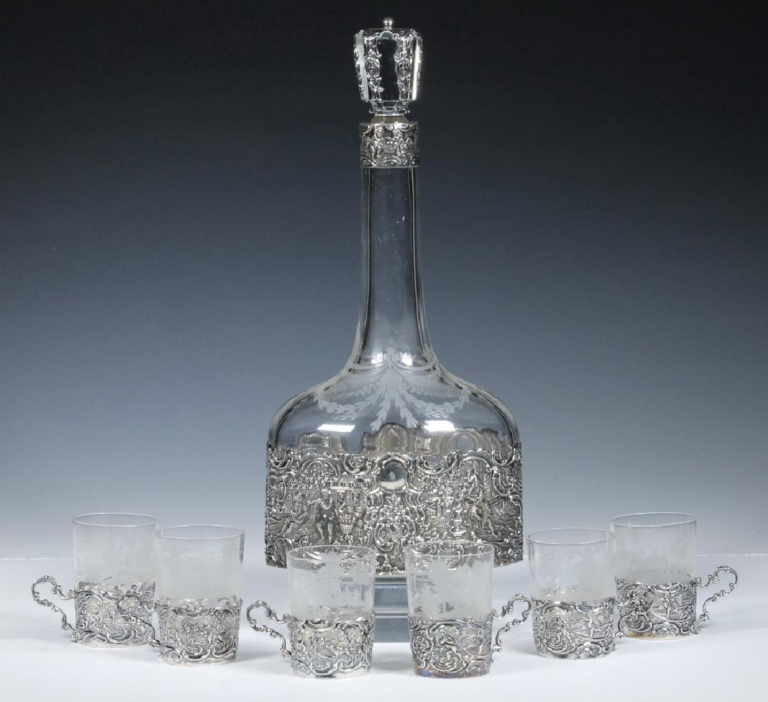 SILVER MOUNTED CRYSTAL DECANTER & (6) GLASSES: (7) Piece Silver Mounted Crystal Lot, including: Late 19th c. etched and cut crystal decanter with stopper, reticulated sterling mounts with figural motifs by Mauser Manufacturing Co. (New York, NY, 1