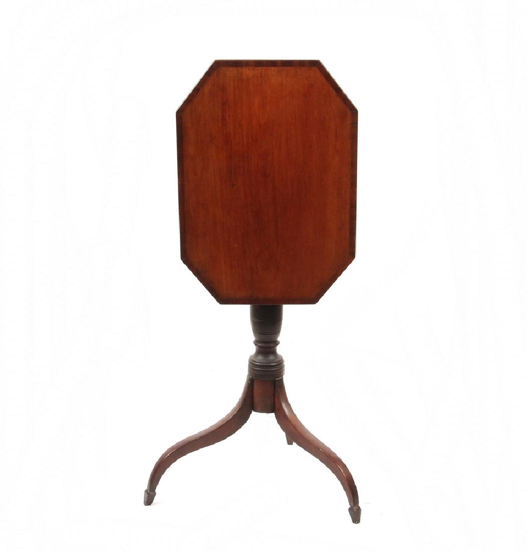 FEDERAL PERIOD COFFIN SHAPED TILT TOP TABLE: Circa 1815, Central East Coast, mahogany with cross-banded edge, retaining the original latch, with scribed ring and urn turned post, high arched tripod base with carved and tapered square legs ending