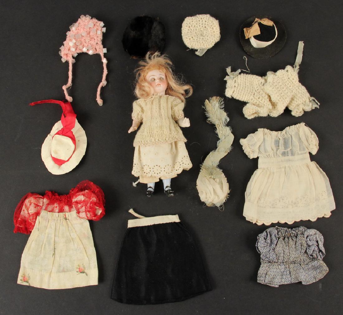 BISQUE HEAD DOLL WITH WARDROBE: Small Bisque Head Doll, with sleep eyes, painted features, blonde hair, composition body, with three outfits, one sweater and six hats in addition to what she is wearing, 6" high. Hairline crack to th
