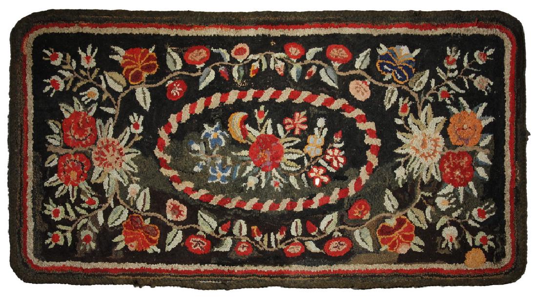 FLORAL HOOKED RUG - 33 3/4" x 62 1/2": Early 20th c. Floral Hooked Rug with Floral and Vine Decoration, black ground with brown, red and tan outer edge, central oval cartouche. Old repairs, small holes, areas of edge separation and stitchi