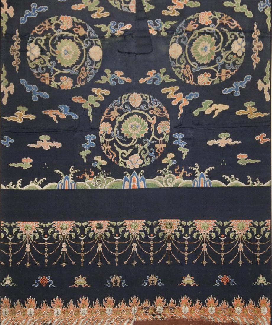 RARE FRAMED PANEL OF AN 18TH C. BUDDHIST DANCE ROBE: China, circa 1730 AD, Embroidered Silk Cloth with skulls, flames and floral rondels, on a rich deep blue ground. The quality of this unusual weaving suggests it was made for use at the court, probably