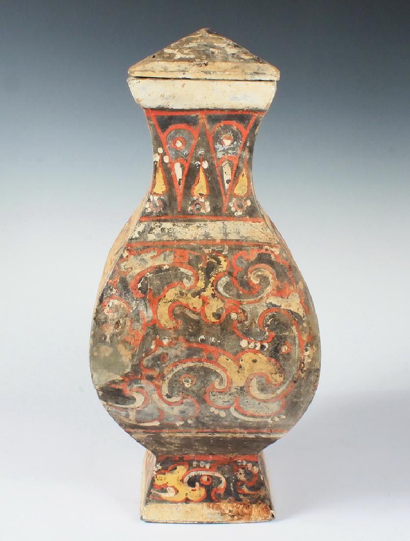 CHINESE POTTERY VASE WITH COVER: Han Dynasty (206 BC - 220 AD) Funeral Urn, in Hu form, square profile, with deep foot and pyramidal top, decorated in orange, yellow and creme slip, featuring a Tao Tie mask on each side, 17 3/4" x 7 